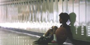 a lone boy sitting on the floor in front of lockers