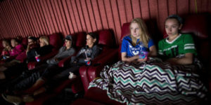 teenagers sitting in the back row of a movie theater