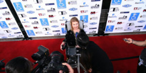 woman in wheelchair on the red carpet answering reporter questions