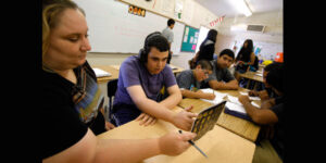 student wearing headphones working with an adult