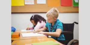 boy in wheelchair working on classwork next to gen ed student