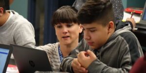 adult helping out a student looking at a laptop