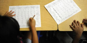 kids filling out paper assignment at table