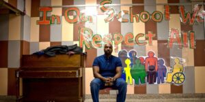 teacher in front of art display that says respect all