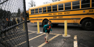 young student kid wearing a backpack in front of a school bus