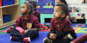 young student kids sitting cross legged in a classroom