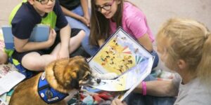 therapy dog reading a book with students and teacher