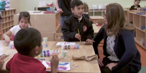 teacher with young students who are painting