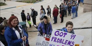 teachers and children holding signs of protest for teacher walkout