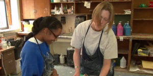 blind female art teacher helping young blind female student