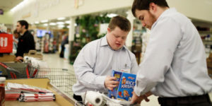 young man helping older man to bag groceries